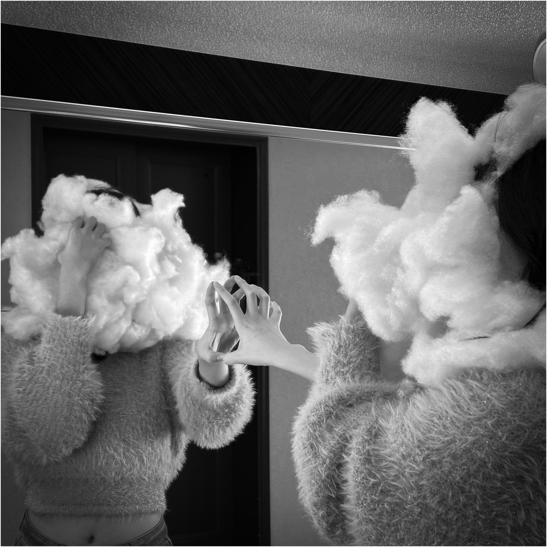 A black and white mirror self-portrait, the head wrapped in cotton wool