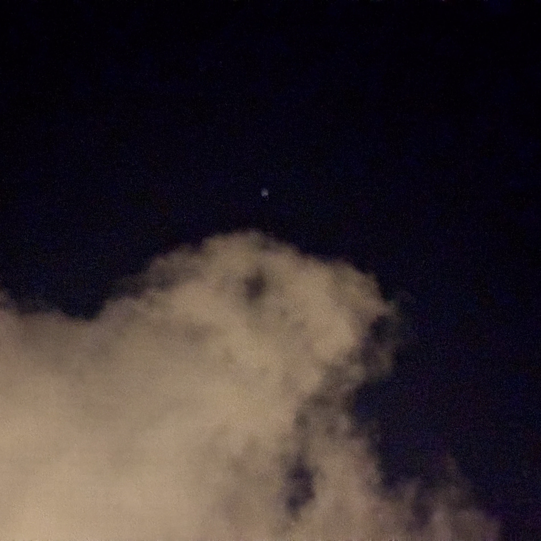 A grainy night sky, one star above the lit edge of a heavy cloud