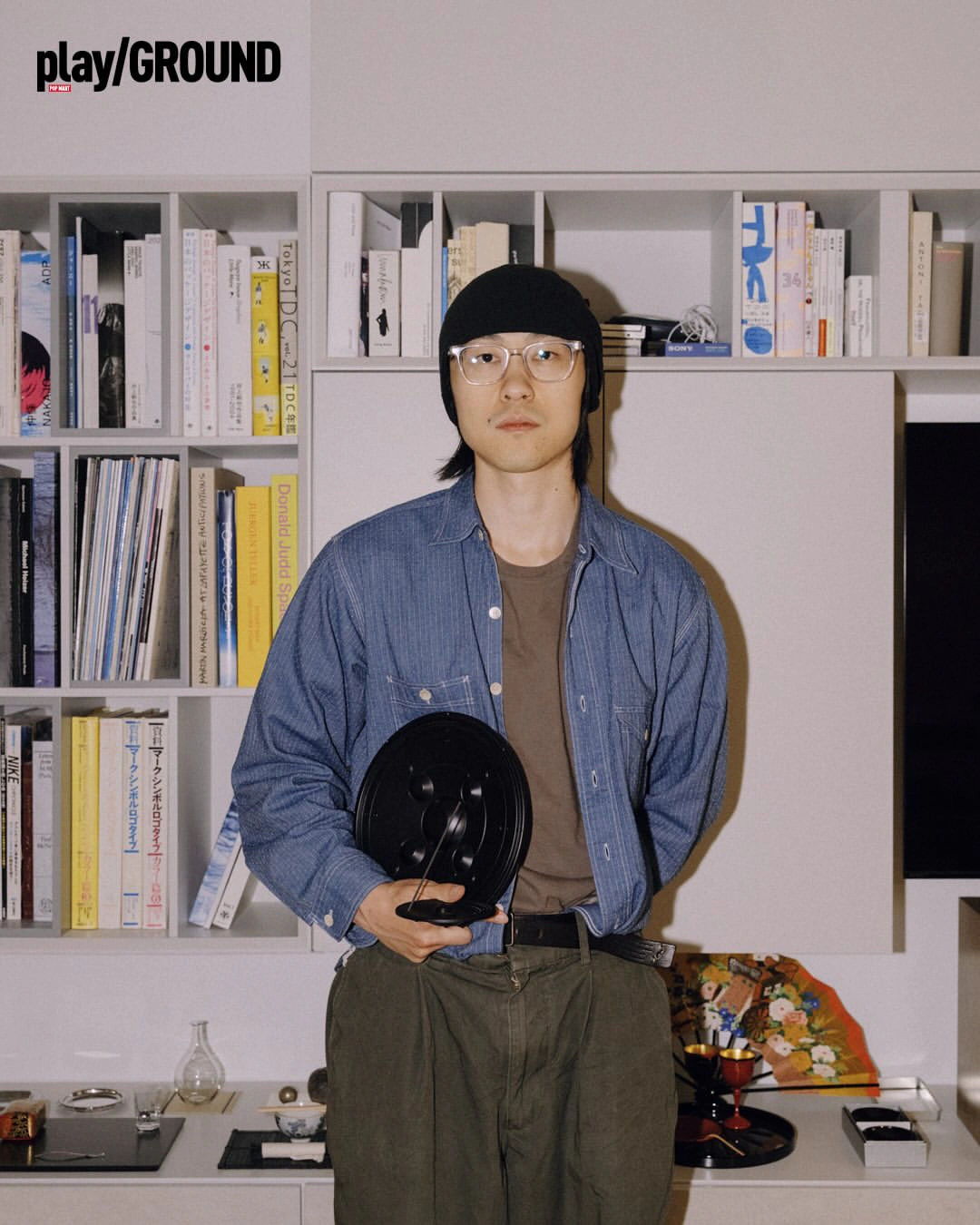 Gao Han holding a black vinyl in front of a bookshelf